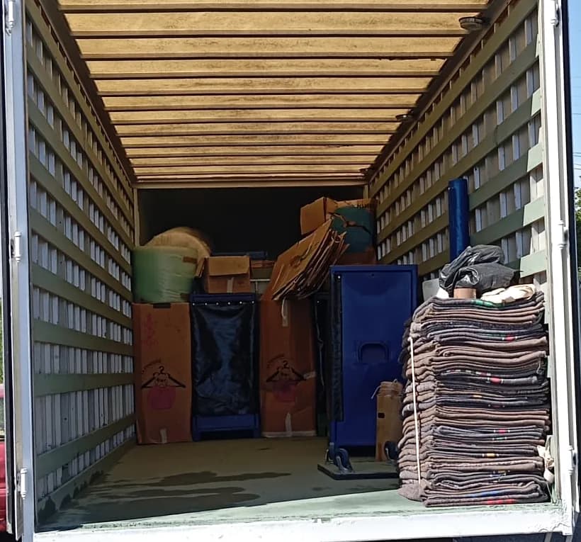 Caisse de camion de déménagement chargée : cartons, mobilier protégé et pile de couvertures